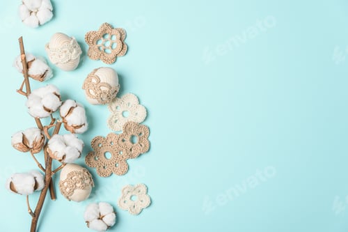 Preview: Craft eggs, knitted and cotton flowers on blue background. Top view. Copy space