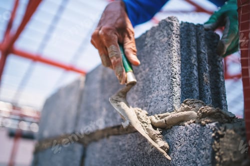 Preview: man is using trowel to spread cement on brick wall