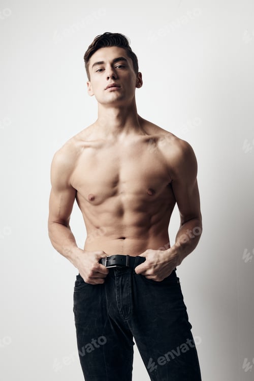 Preview: A guy with a naked torso and in jeans on a light background cropped view