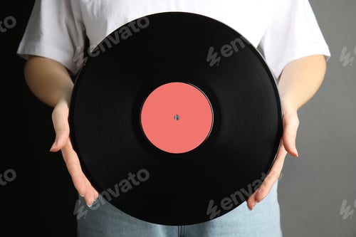 Preview: Woman holding vintage vinyl record on grey background, closeup