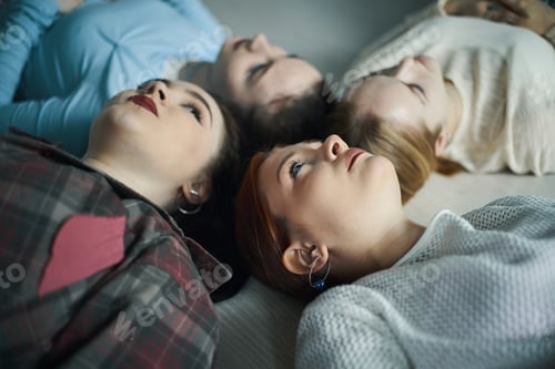 Preview: Four Young Women Lie Together Looking Upward