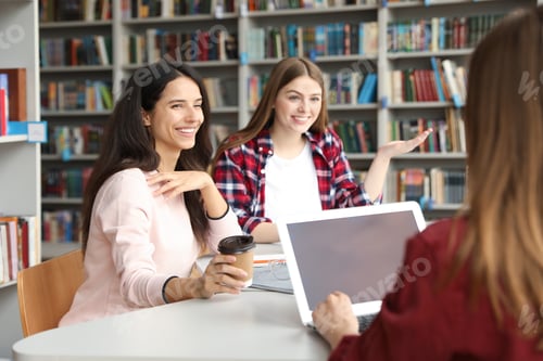 Preview: Young people discussing group project at table in library