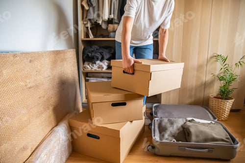 Preview: Person packing cardboard boxes for home relocation