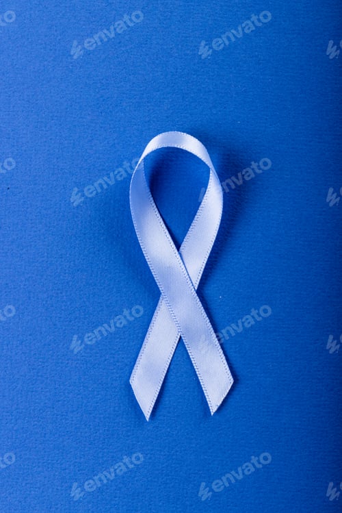 Preview: Close-up of blue stomach cancer awareness ribbon isolated over blue background, copy space
