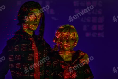 Preview: cosplay students in colorful neon projection of hieroglyphs on blue indigo backdrop in studio