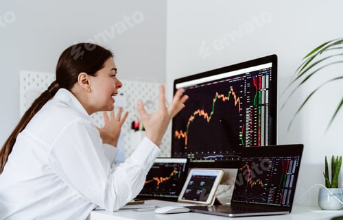 Preview: Young upset girl cryptocurrency trader sitting at desk depressed looking at stocks with despair