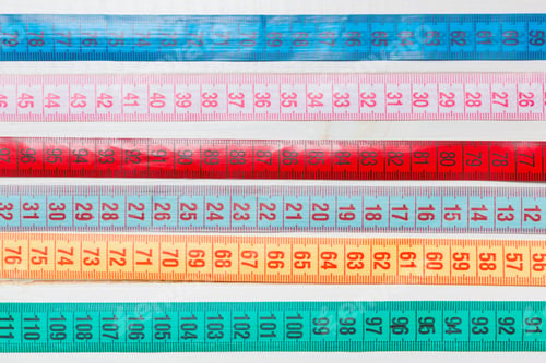 Preview: Close up of a group of colorful measure tapes lying in rows as a background.