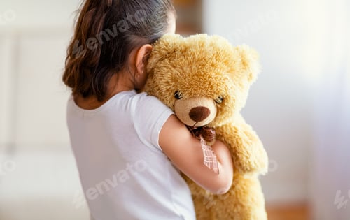 Preview: Unrecognizable Kid Girl Embracing Teddy Bear Toy Standing Alone Indoor