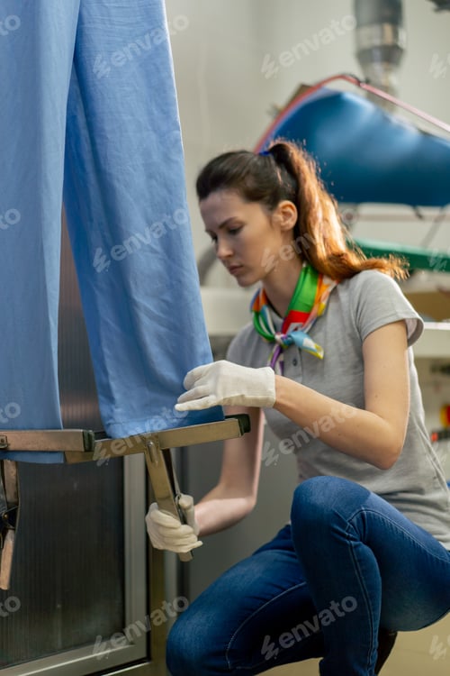 Preview: professional dry cleaner young girl takes a suit out of the dryer for finishing by hand press