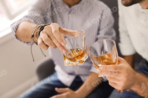 Preview: Friends toasting with glasses of whiskey indoors, closeup