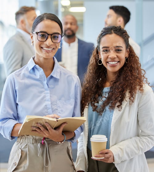 Preview: Portrait of two businesswomen standing in an office with their colleagues in the background