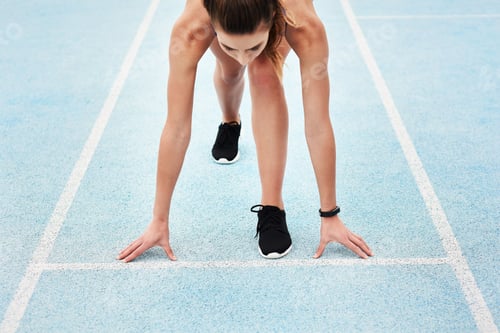 Preview: Cropped shot of an unrecognizable young female athlete standing in the set position on the track