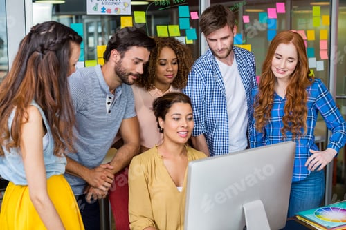 Preview: Smiling graphic designers interacting with each other while working at desk