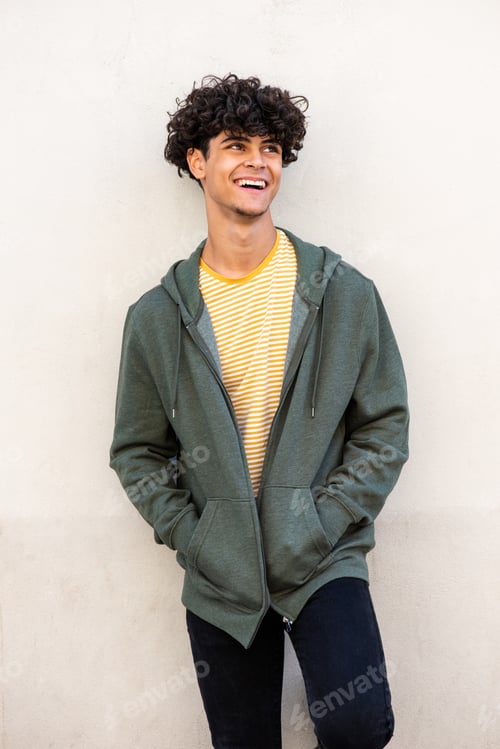 Preview: trendy young North African man laughing by white wall