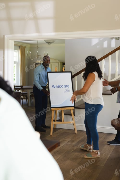 Preview: Welcoming guests, senior man and woman setting up welcome sign at home