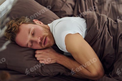 Preview: Man sleeps on the bed. Interior and design of beautiful modern bedroom at daytime