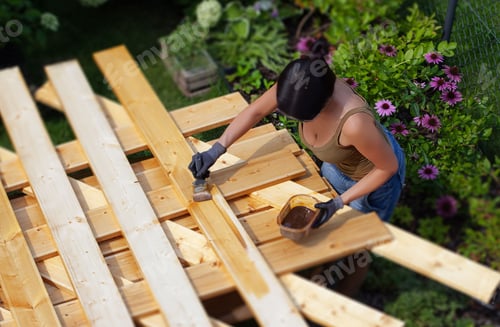 Preview: Woman painting wooden planks in the garden