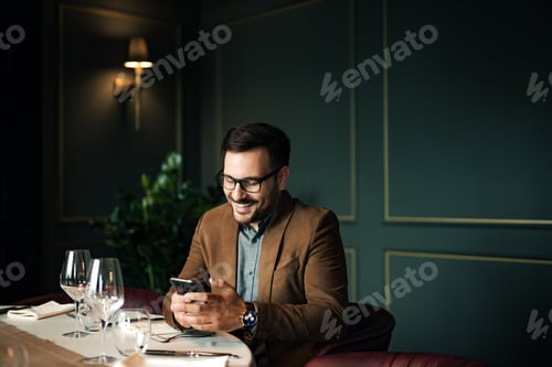 Preview: Handsome smiling man using smart phone at restaurant, portrait, copy space.
