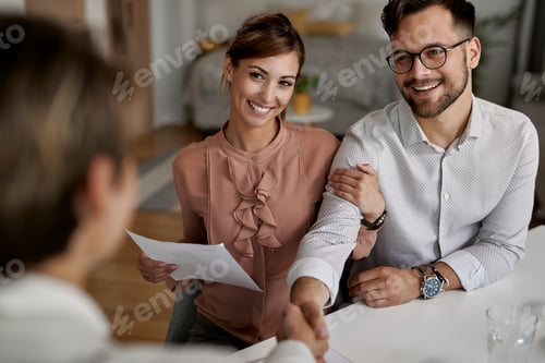 Preview: Young happy couple shaking hands with their insurance agent.