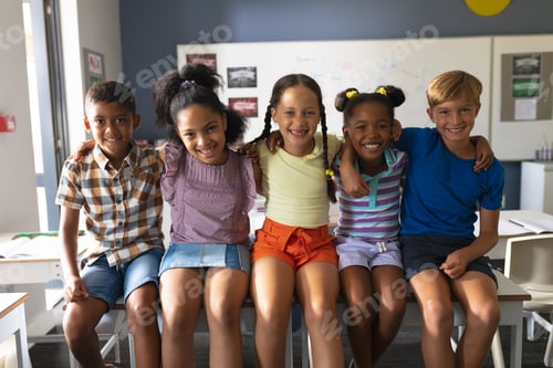Preview: Portrait of smiling multiracial elementary school students sitting with arm around in classroom