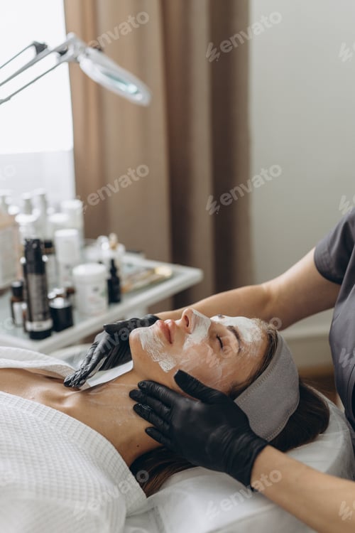 Preview: Close up of cosmetologist make face mask for woman client in saloon.Dermatology,beauty concept.