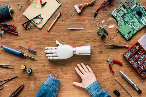 Preview: cropped image of man with amputee sitting at table with prosthetic arm surrounded by instruments