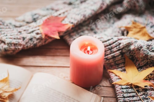 Preview: Burning candle, open book, autumn leaves and knitted sweater on wooden table. Fall concept. Top view