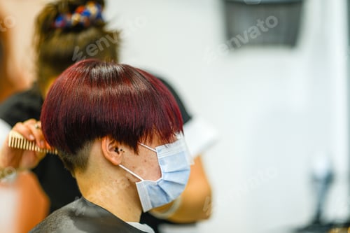 Preview: Closeup shot of a female getting her hair done wearing a face mask - concept of the new normal
