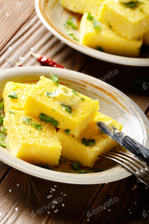 Preview: Polenta with butter and greens on clay dish on wooden rustic tab