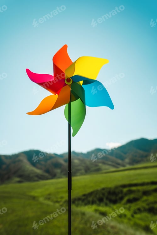 Preview: Symbol of clean green energy, pinwheel ibackground of the sky and a green landscape