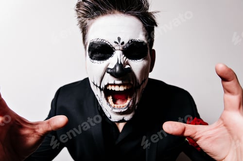 Preview: Guy with painted face in form of skull shouts violently, posing in frightening way