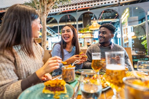 Preview: Happy friends eating burgers and drinking beer at restaurant