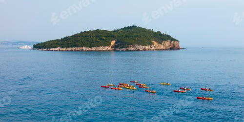 Preview: Panoramic photo of sea kayaking in Dubrovnik, tourists kayak past Buza Bar and Lokrum Island, Dubrov