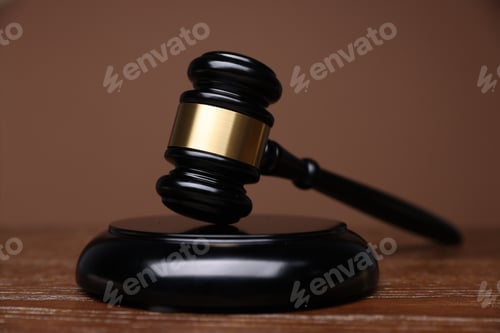 Preview: Judge's gavel and sound block on wooden table against brown background, closeup