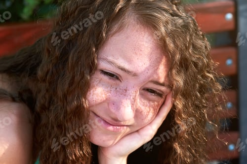 Preview: Thoughtful portrait of a teenage girl with freckles on her face. Girl props her face with her hand.