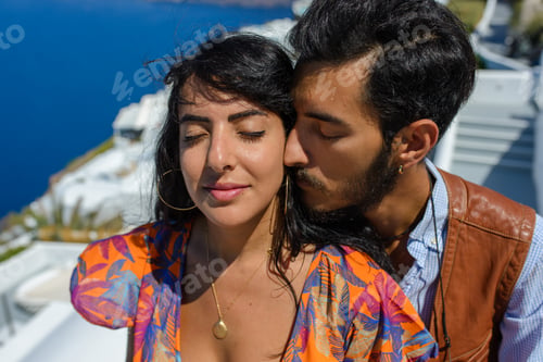 Preview: A man and a woman kiss against the backdrop of Skaros Rock on Santorini Island.