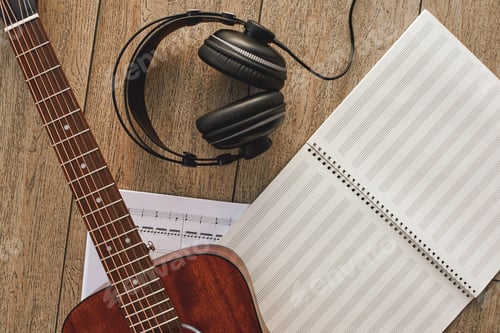 Preview: Close up view of guitar, professional headphones and musical notes laying on the wooden floor