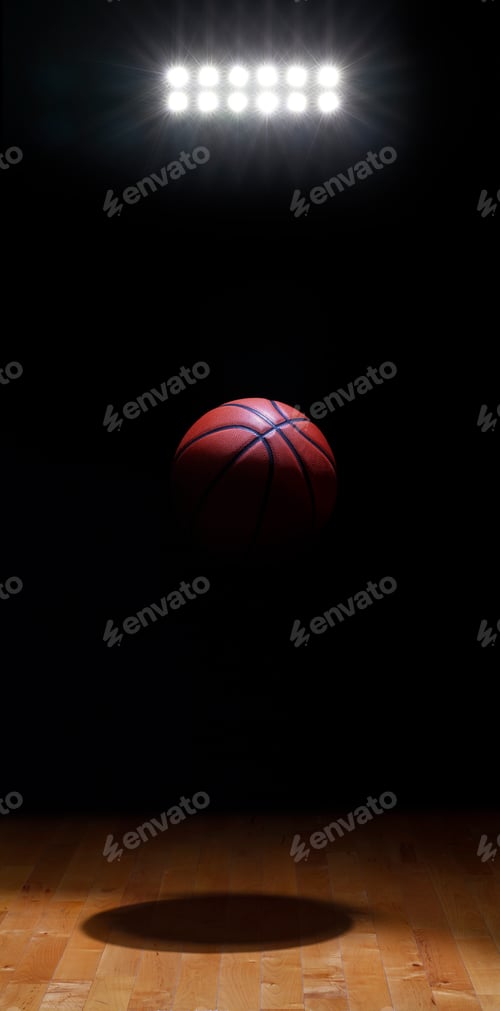 Preview: Basketball spot lit suspended against black background with lights above hardwood court floor