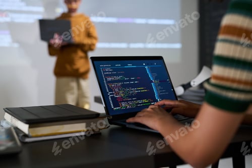 Preview: Young Adult Caucasian Woman Writing Code on Laptop While Teenager Standing Nearby
