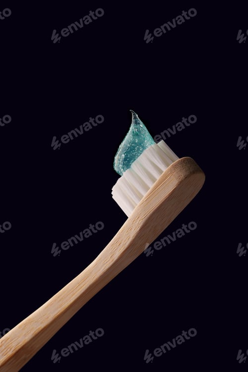 Preview: Bamboo toothbrush with transparent blue toothpaste on a dark blue background.