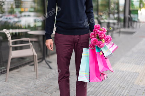 Preview: Romantic man with pink flowers and shopping bags on brick background. Woman's day. Valentine'