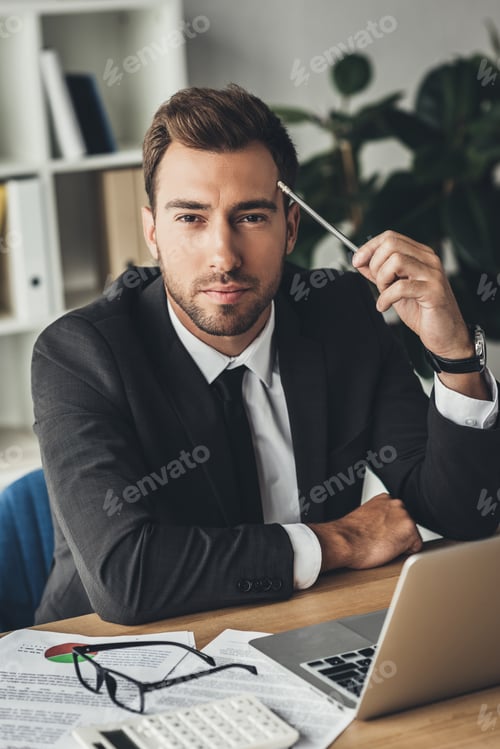 Preview: handsome young businessman at workplace looking at camera