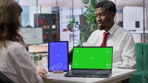Preview: HR staff discussing with applicant next to mockup chroma key screens