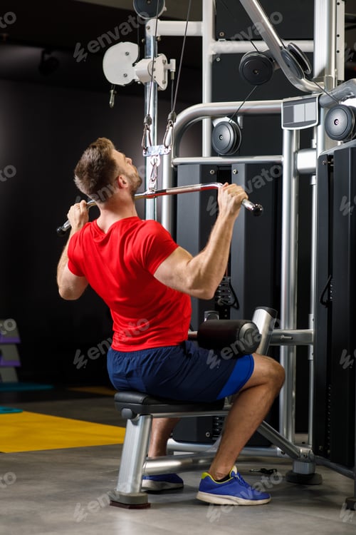 Preview: Young muscular man pulling up on horizontal bar in a gym
