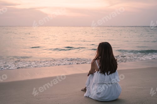 Preview: Lonely young asian woman sitting on the beach at sunset