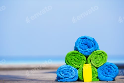 Preview: Close up of colorful towels and sunscreen bottle background the sea