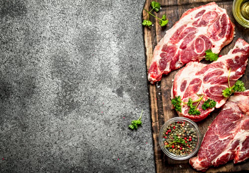 Preview: Raw meat background. Raw steak with herbs and spices on the old Board. On rustic background.