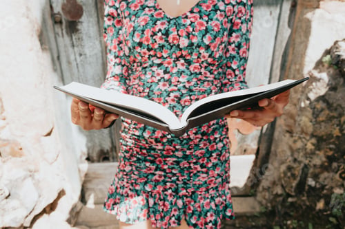 Preview: Close image of a woman in a dress grabbing a book while reading it with copy space