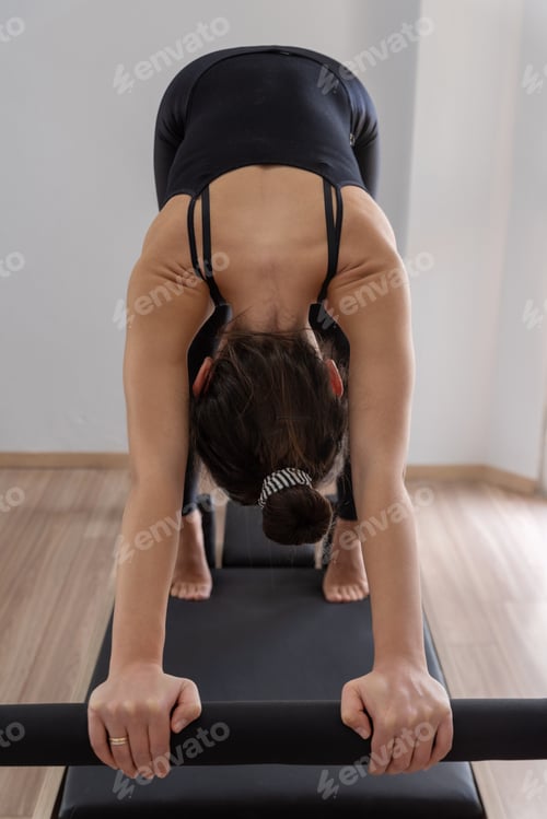 Preview: Young woman exercising on pilates reformer bed