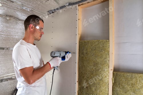 Preview: Worker in goggles with screwdriver working on insulation.
